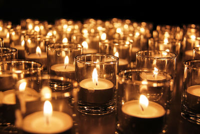 Close-up of lit tea light candles in church