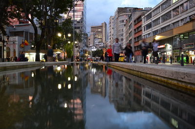 People in illuminated city against sky