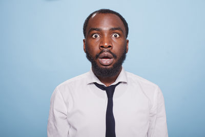 Portrait of young man standing against blue background