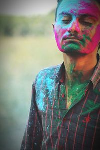 Young man with colorful powder paint on face during holi