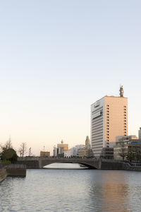 Buildings by river against sky in city