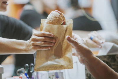 Sandwich being passed to a customer from a food truck.