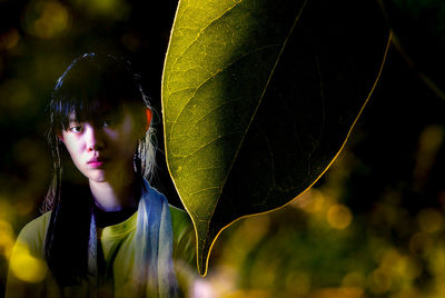 Portrait of teenage girl standing by leaf