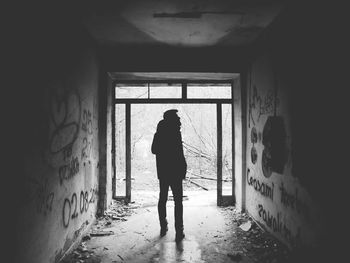 Rear view of woman standing in abandoned building
