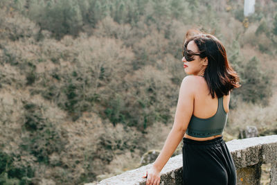 Young woman looking away while sitting on rock