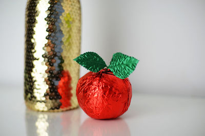 Champagne bottle and red candy against white background