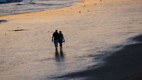 Rear view of people walking on beach