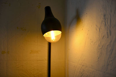 Low angle view of illuminated light bulb hanging from ceiling