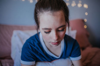 Close up of tween girl sitting on bed looking down