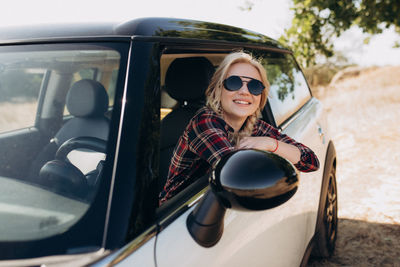 Portrait of smiling young woman sitting in car