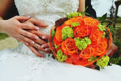 Midsection of bride and groom with bouquet during wedding ceremony