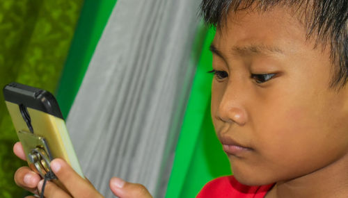 Close-up of boy using mobile phone at home