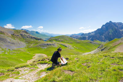 Rear view of man walking on mountain against sky