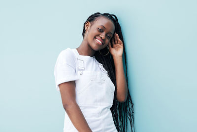 Portrait of young woman standing against blue background