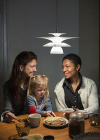 Lesbian couple and girl having breakfast at dining table