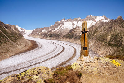 Road leading towards mountains against clear blue sky