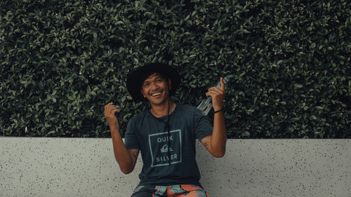 Portrait of smiling young man standing against plants