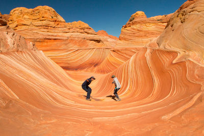 Full length of man and woman at rock formations in desert