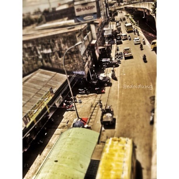 transportation, transfer print, mode of transport, high angle view, auto post production filter, land vehicle, in a row, day, building exterior, city, incidental people, selective focus, built structure, travel, outdoors, architecture, men, large group of objects, street, machinery