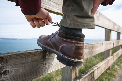 Low section of man by railing on bridge against sky
