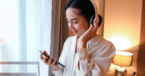 Young woman using mobile phone while listening music