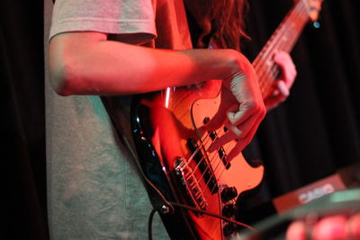 Midsection of man playing guitar in event