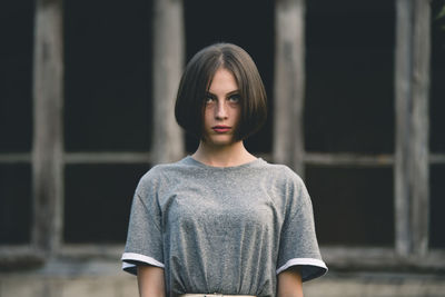 Beautiful young woman looking away while standing against windows