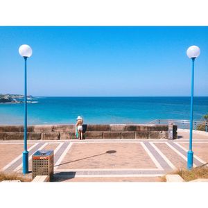 People at swimming pool against clear blue sky