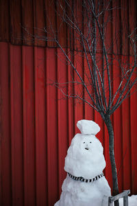 Snowman by bare tree