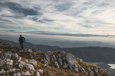 Man standing on rock against sky