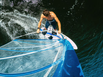 Wide-angle shot of adult man windsurfing on lake wallersee, austria