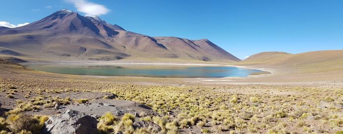 Scenic view of landscape and mountain lake against clear blue sky