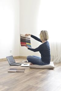 Side view of woman sitting on book at home