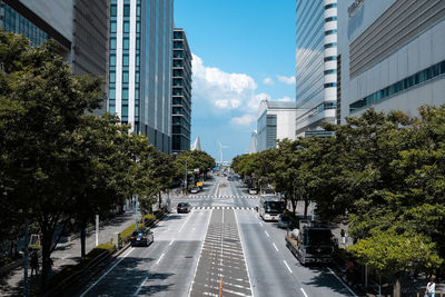 Road amidst trees and buildings against sky