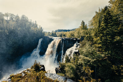 Panoramic view of waterfall in forest against sky