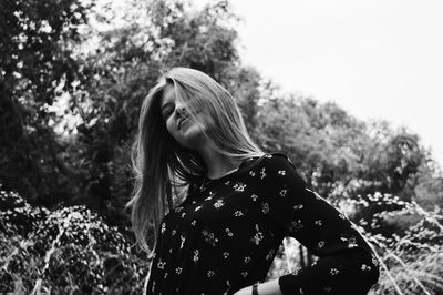 Low angle view of young woman standing by tree
