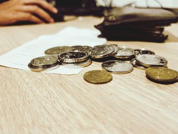 Close-up of hand holding coins on table