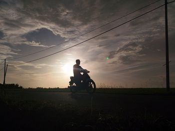 Silhouette man riding bicycle on field