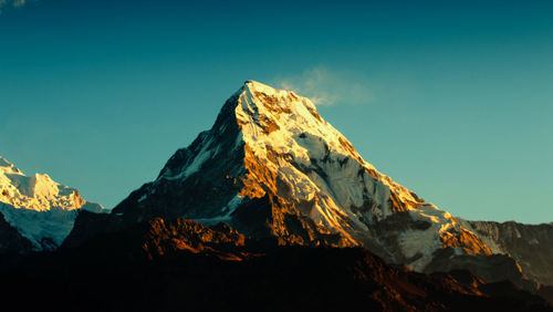 Low angle view of snowcapped mountains against clear sky