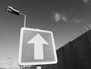 Low angle view of street light and road sign against sky