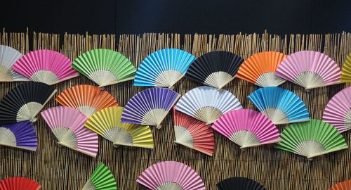 Multi colored fans displayed against wall for sale in market