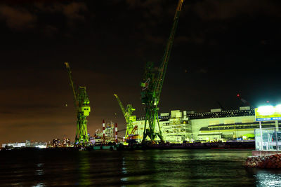 Illuminated commercial dock by river against sky at night