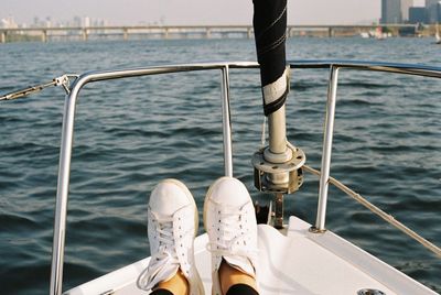 Low section of woman wearing white shoes sitting in boat on sea