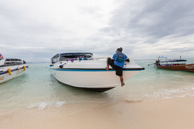 Men on boat in sea against sky