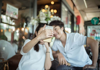 Young woman taking selfie with man at restaurant