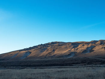 Scenic view of arid landscape against clear blue sky