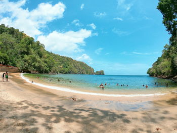 Group of people at beach against clear blue sky