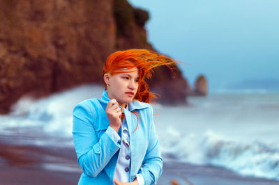 Young woman standing at beach against sky