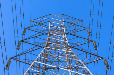 Low angle view of electricity pylon against blue sky