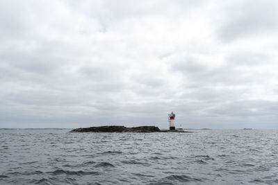 Lighthouse by sea against sky